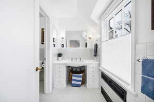 Bathroom with tile walls, radiator heating unit, tile patterned flooring, and a sink