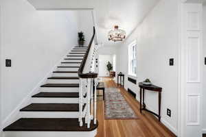Stairway with a chandelier and wood finished floors