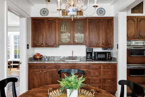 Bar featuring double wall oven, a sink, a notable chandelier, visible vents, and black microwave
