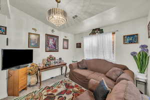 Living room with a chandelier, visible vents, and carpet floors