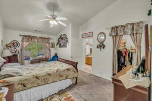 Bedroom featuring lofted ceiling, ceiling fan, visible vents, a spacious closet, and carpet floors
