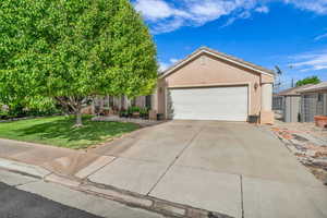 View of front facade with driveway, fence, an attached garage, stucco siding, and a front lawn