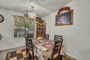 Carpeted dining area featuring a notable chandelier, baseboards, and visible vents