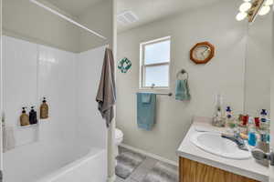 Bathroom featuring toilet, tile patterned floors, visible vents, baseboards, and vanity