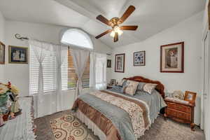 Bedroom with ceiling fan, lofted ceiling, and carpet flooring