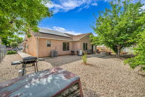 Rear view of house featuring a tiled roof, a patio, stucco siding, a fenced backyard, and roof mounted solar panels