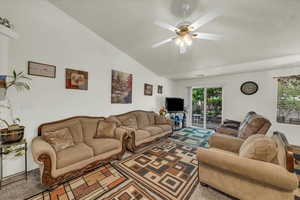 Living area with a wealth of natural light, lofted ceiling, ceiling fan, and carpet floors