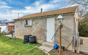 Back of property featuring a lawn, entry steps, and concrete block siding