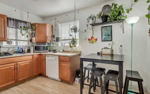 Kitchen with light countertops, a sink, stainless steel microwave, and dishwasher