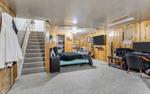 Carpeted bedroom featuring wooden walls