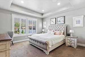 Bedroom featuring a tray ceiling, recessed lighting, baseboards, and carpet floors