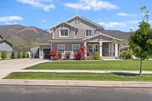 Craftsman house featuring a mountain view, board and batten siding, a front yard, a porch, and driveway