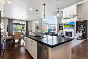 Kitchen featuring a sink, dark countertops, plenty of natural light, a textured ceiling, and appliances with stainless steel finishes