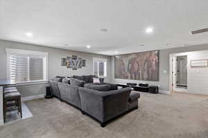 Carpeted living area with baseboards, recessed lighting, visible vents, and a textured ceiling