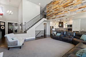 Living area with an inviting chandelier, visible vents, baseboards, and a towering ceiling