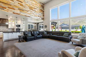 Living room featuring a towering ceiling, dark wood-style floors, and plenty of natural light