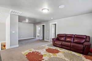 Living room featuring baseboards, a textured ceiling, visible vents, and carpet