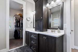 Bathroom with double vanity, baseboards, a spacious closet, and a sink