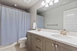Full bath featuring double vanity, toilet, visible vents, and a sink