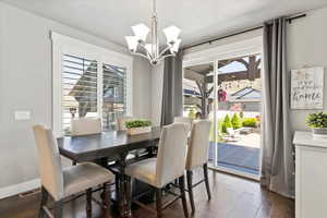Dining space featuring baseboards, a notable chandelier, visible vents, and dark wood-type flooring