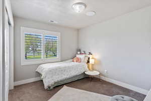 Carpeted bedroom featuring baseboards and visible vents