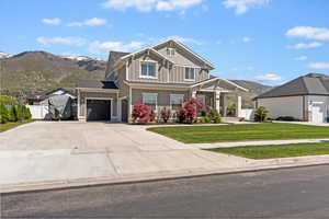 View of front facade featuring a mountain view, a garage, a front lawn, board and batten siding, and driveway