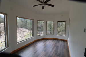 Unfurnished sunroom featuring a wealth of natural light, baseboards, and wood finished floors