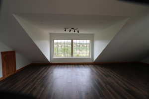 Bonus room featuring baseboards and dark wood-type flooring