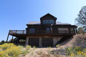 Rear view of house featuring stairway, a deck, a garage, and metal roof