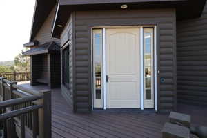 Doorway to property featuring log veneer siding and a wooden deck