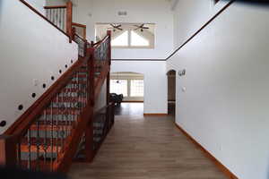 Stairs featuring ceiling fan, arched walkways, baseboards, and wood finished floors