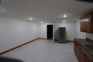 Kitchen with freestanding refrigerator, dark countertops, baseboards, and recessed lighting