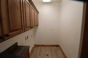 Washroom featuring baseboards, light wood-style floors, and cabinet space