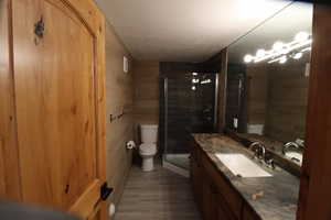 Bathroom with a stall shower, toilet, visible vents, vanity, and wood finished floors