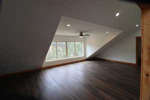 Additional living space with baseboards, dark wood-style flooring, and ceiling fan