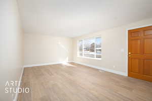 Empty room featuring light wood-style floors, visible vents, and baseboards
