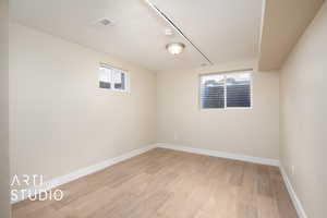 Empty room with baseboards, light wood-style flooring, visible vents, and plenty of natural light