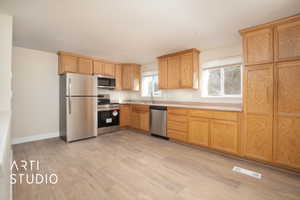 Kitchen with appliances with stainless steel finishes, visible vents, light countertops, baseboards, and light wood-style floors