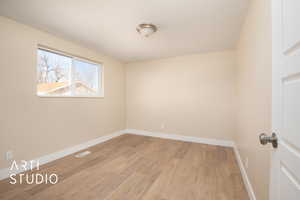 Unfurnished room featuring visible vents, light wood-style flooring, and baseboards