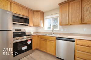 Kitchen with a sink, stainless steel appliances, light countertops, and light wood-style flooring