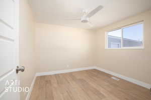 Spare room featuring light wood finished floors, baseboards, a ceiling fan, and visible vents