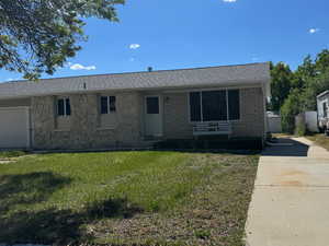 Ranch-style home featuring a front yard, concrete driveway, brick siding, stone siding, and a shingled roof