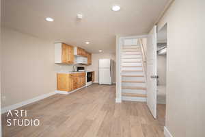 Kitchen with a sink, baseboards, white appliances, light countertops, and recessed lighting
