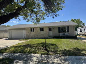 Single story home featuring an attached garage, a front lawn, and concrete driveway