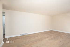 Empty room featuring baseboards, light wood-type flooring, and visible vents