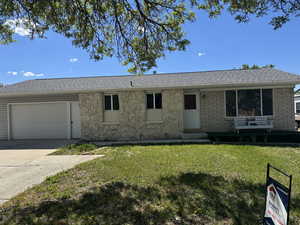 Ranch-style house featuring an attached garage, a front lawn, driveway, entry steps, and roof with shingles