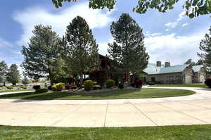 View of front of home featuring a chimney, stone siding, a front lawn, and metal roof
