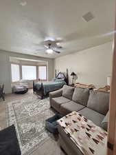 Carpeted bedroom with a textured ceiling, visible vents, and a ceiling fan
