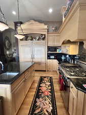 Kitchen featuring arched walkways, light wood finished floors, appliances with stainless steel finishes, and a sink