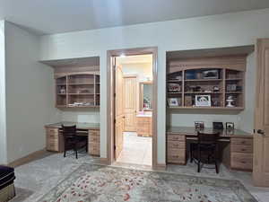 Office space featuring built in study area, light carpet, and baseboards